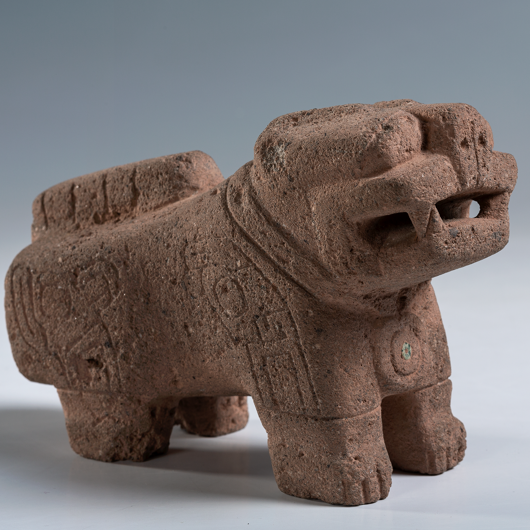 A small puma carved from grey-brown stone and decorated with lines.